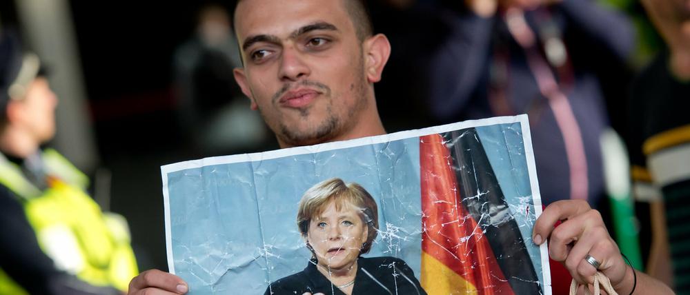 Bei den Asylbewerbern beliebt: Ein Flüchtling hält am Hauptbahnhof München ein Foto von Angela Merkel in den Händen.
