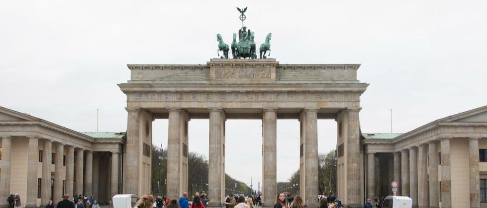Touristen stehen vor dem Brandenburger Tor. 
