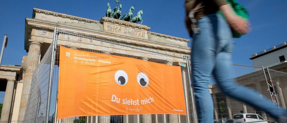 Ein Banner mit dem Logo des Kirchentags an einem Absperrzaun vor dem Brandenburger Tor.