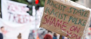 "Rassistischer Staat, rassistische Polizei, Schande über Euch" steht auf einem Schild bei der Gerhart-Hauptmann-Schule.