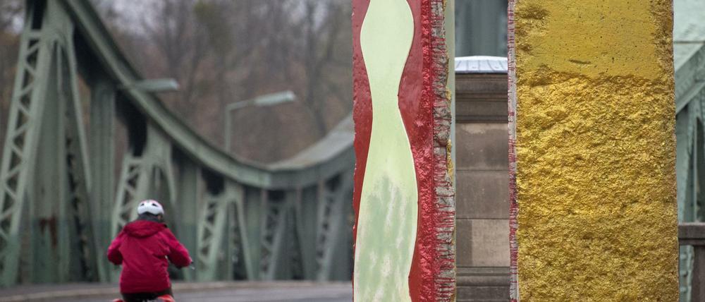 Originalteile der ehemaligen Berliner Mauer stehen in Potsdam (Brandenburg) vor der Kulisse der historischen Glienicker Brücke. 