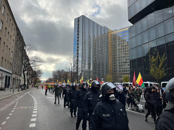 Mehrere behelmte Polizisten begleiten den Protestzug entlang des Axel-Springer-Gebäudes.