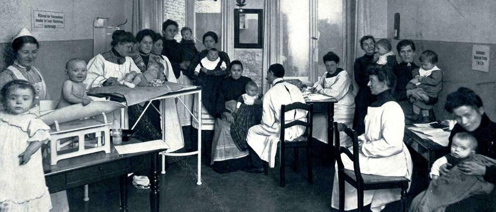 Das Behandlungszimmer für Säuglinge im Charlottenburger Pestalozzi-Fröbel-Haus: Zu sehen sind Mütter mit ihren Babys und medizinisches Personal.