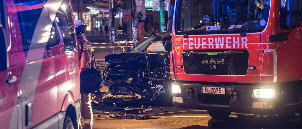 Ein zerstörter Pkw steht am 27.03.2017 in Berlin am Frankfurter Tor zwischen zwei Einsatzfahrzeugen der Polizei.