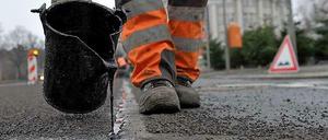 Straßenbild: Ein Bauarbeiter bessert Rillen und Löcher im Belag aus.