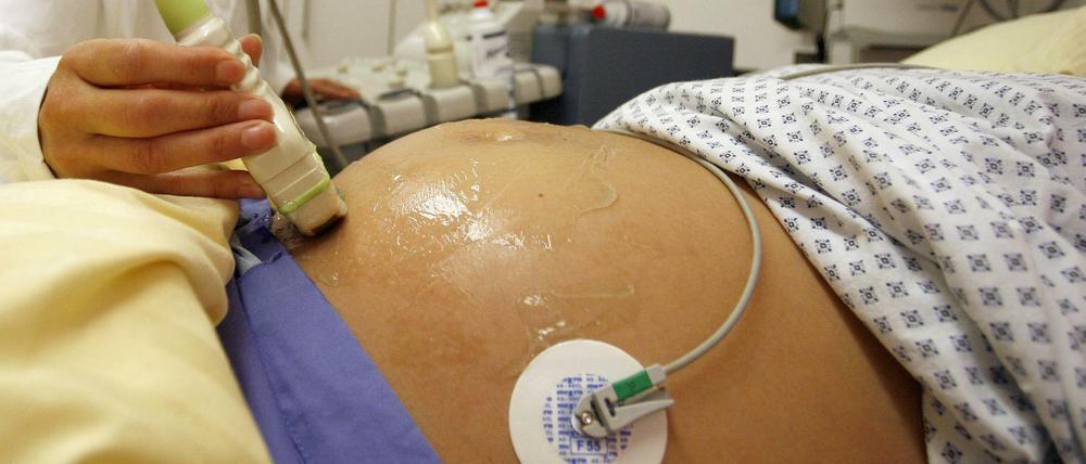 Eine Hebamme führt an einer schwangeren Patientin eine Ultraschall-Untersuchung durch. 