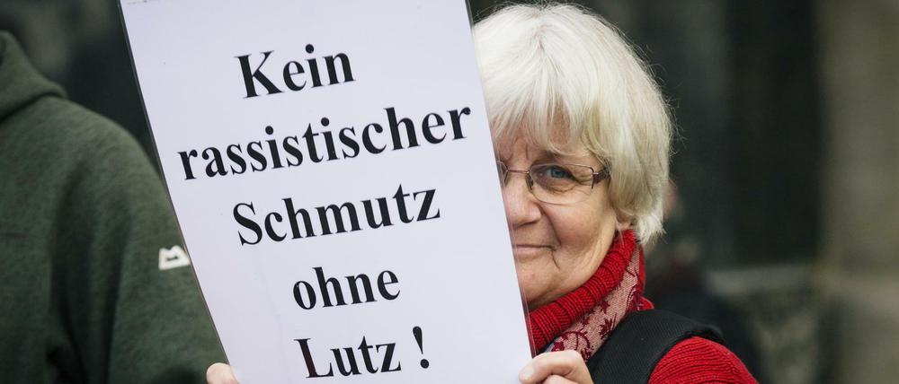 Die Menschenrechts-Aktivistin Irmela Mensah-Schramm steht mit einem Schild neben der Pegida-Kundgebung in Dresden.