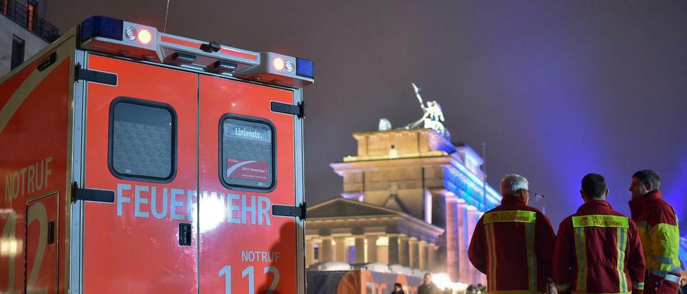 Einsatzkräfte der Berliner Feuerwehr stehen auf der Festmeile vor dem Brandenburger Tor. 