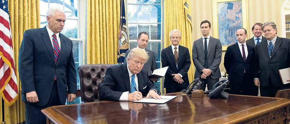 Die Mannschaft. Wenn Donald Trump Dekrete unterzeichnet, sind Vize-Präsident Mike Pence (links), Schwiegersohn Jared Kushner (4.v.r.), Strategieberater Stephen Bannon (ganz rechts) und Stabschef Reince Priebus (halbrechts hinter Trump) fast immer dabei.