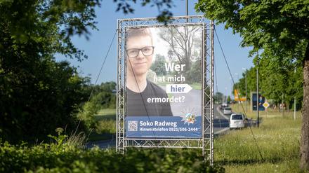 "Wer hat mich hier ermordet?" steht auf einem großen Plakat mit Foto des Opfers neben dem Tatort.
