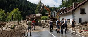 Menschen säubern eine Straße und ein Haus im slowenischen Raduha vom Hochwasserschutt.