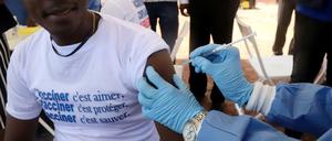 Ein Mitarbeiter der Weltgesundheitsorganisation (WHO) setzt einem Mann im Rahmen einer Impfkampagne eine Spritze an den Oberarm. 