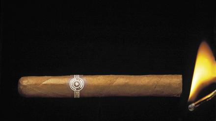 Eine Montecristo-Zigarre wird mit einem Streichholz angezündet.