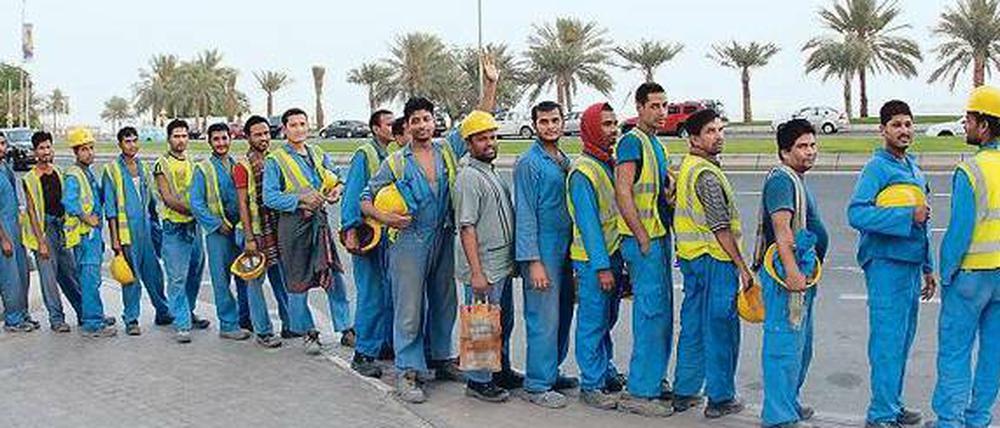 Arbeitsmigranten warten nahe der Corniche im Herzen Dohas auf ihren Bustransfer zur Baustelle.
