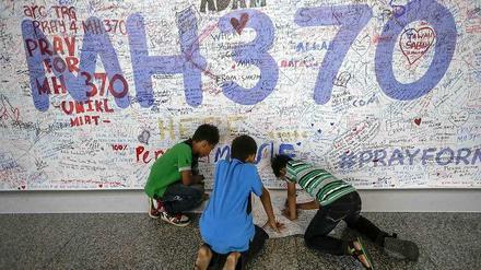 Kinder in Kuala Lumpur, Malaysia, vor einer Wand mit aufgemalten Bekundungen der Hoffnung für die Insassen des verschollenen Flugs MH370.