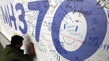 Ein Passagier schreibt am 13.03.2014 eine Nachricht an Passagiere des verschwundenen Malaysia-Airlines-Fluges mit der Flugnummer MH370 auf ein Banner am internationalen Flughafen von Kuala Lumpur, Malaysia.
