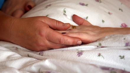 Hospiz: Hände auf der Bettdecke einer Bewohnerin.