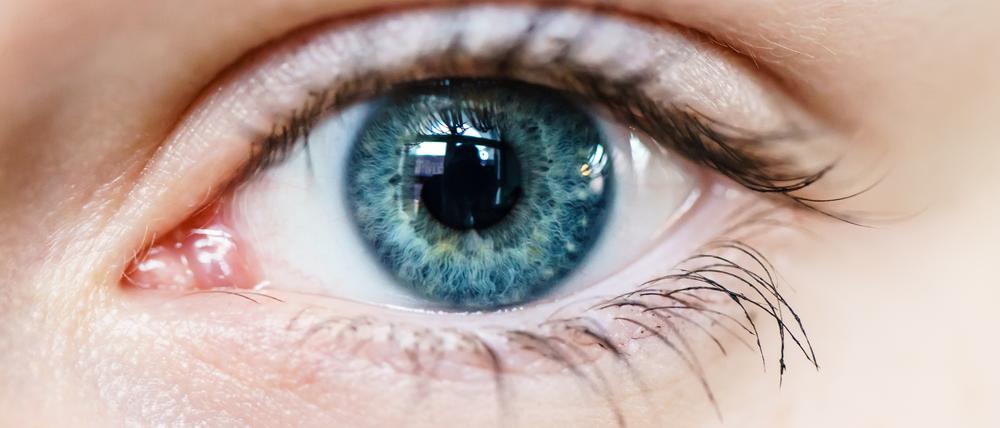 Nahaufnahme eines Auges mit blauer Iris. 