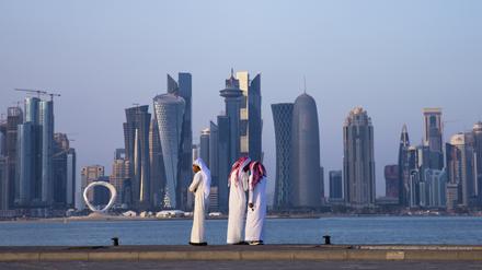 Drei Männer stehen vor der Skyline in Doha. +++ dpa-Bildfunk +++