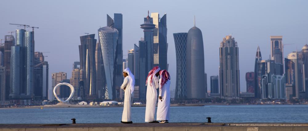 Drei Männer stehen vor der Skyline in Doha. +++ dpa-Bildfunk +++