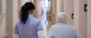 Eine Pflegekraft unterstützt eine Seniorin beim Gehen.