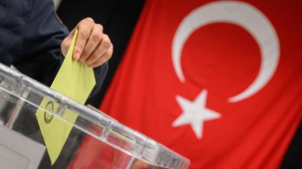 Ein Wähler wirft seinen Wahlumschlag in eine Urne in einem Wahllokal für die türkische Präsidentschaftswahl in der Messe Hannover.