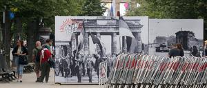 Menschen laufen auf dem Mittelstreifen auf der Straße Unter den Linden und betrachten Großformatige Tafeln mit historischen Fotos des DDR-Volksaufstands von vor 70 Jahren, am 17. Juni 1953. Im Hintergrund das Brandenburger Tor. +++ dpa-Bildfunk +++