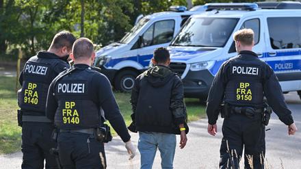 Ein unerlaubt eingereister Migrant wird durch Beamte der Bundespolizei nahe Forst (Lausitz) zum Fahrzeug geführt.