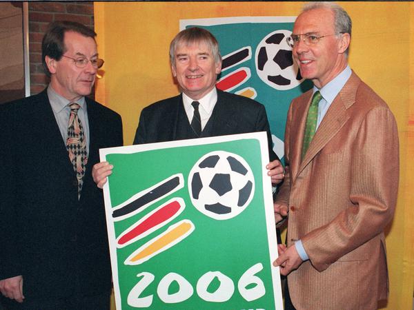 Der damalige Bundesverkehrsminister Franz Müntefering, Bundesinnenminister Otto Schily und DFB-Vizepräsident Franz Beckenbauer präsentieren 1999 ein Werbeschild für die Fußball-WM 2006 in Deutschland.