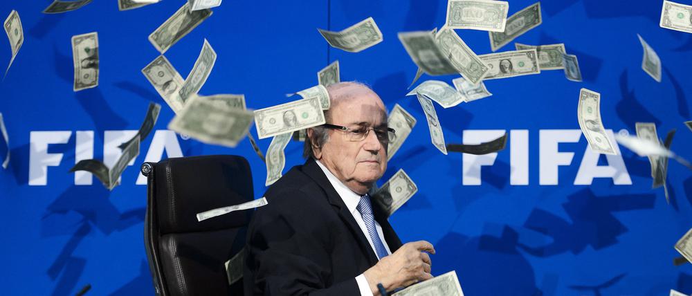 Auf diesem Dateifoto vom 20. Juli 2015 sieht FIFA-Präsident Sepp Blatter zu, wie gefälschte Dollarnoten um ihn herumfliegen, die ein britischer Komiker während einer Pressekonferenz im Hauptquartier des Weltverbandes FIFA in Zürich geworfen hat. 