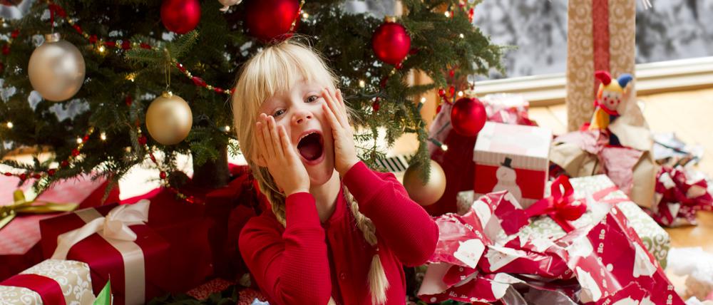 a girl screaming while opening Christmas giftssitting in a pile of wrapping paper