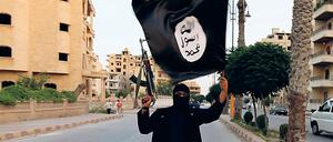 Ein Mitglied des Islamischen Staat (IS) schwenkt eine schwarze Flagge. 