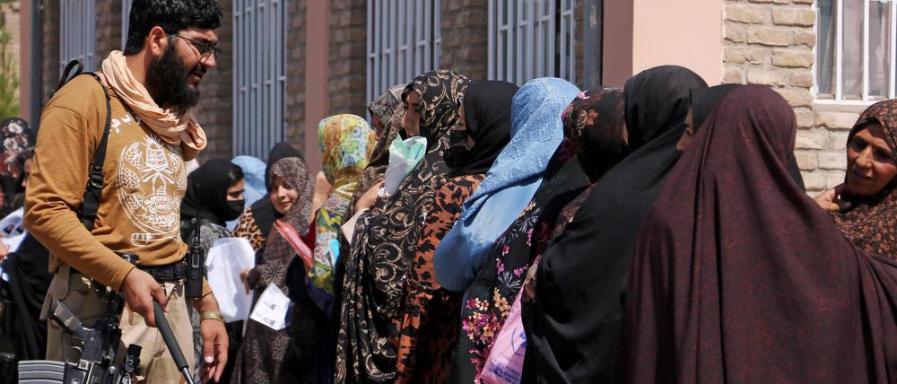 Ein Taliban-Mitglied mit wartenden Frauen in Herat. 