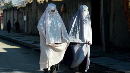 Afghan burqa-clad women walk along a road in Kandahar on March 28, 2024. (Photo by Sanaullah SEIAM / AFP)