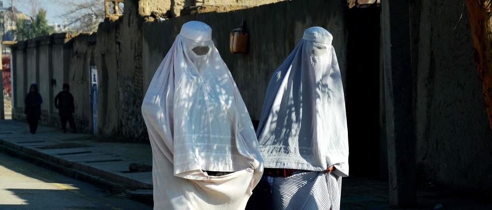 Afghan burqa-clad women walk along a road in Kandahar on March 28, 2024. (Photo by Sanaullah SEIAM / AFP)