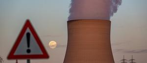 Wasserdampf steigt aus dem Kühlturm des Kernkraftwerks Isar 2 hinter einem Warnschild.