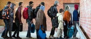 Flüchtlinge, die zuvor mit einem Sonderzug angekommen waren, warten am 03.10.2015 am Bahnhof in Schönefeld (Brandenburg), auf ihre Weiterfahrt zur Unterkunft mit Bussen. 