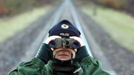 Eine Bundespolizistin überwacht mit einem Fernglas eine Castortransportstrecke in der Nähe von Dannenberg.