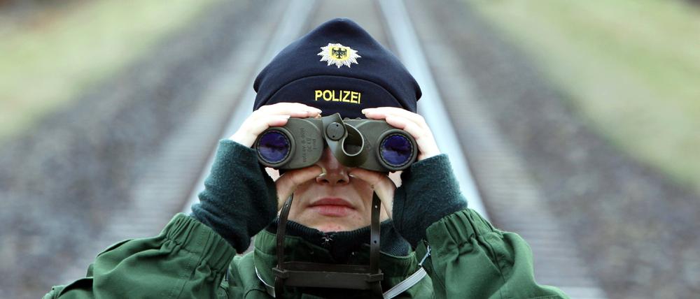 Eine Bundespolizistin überwacht mit einem Fernglas eine Castortransportstrecke in der Nähe von Dannenberg.