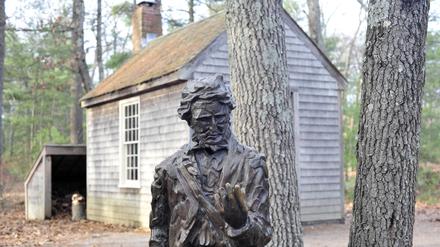 Die nachgebaute Hütte des Schriftstellers Henry David Thoreau nahe Walden Pond, davor eine Statue des Schriftstellers. 
