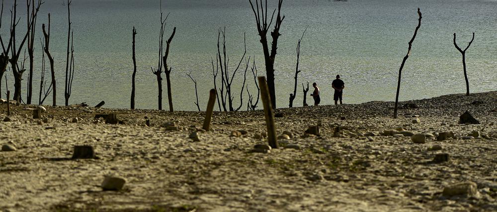 Menschen spazieren am Ufer des von der Dürre betroffenen Yesa-Stausees in Nordspanien entlang. 