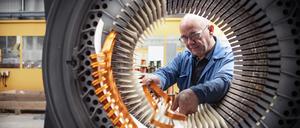 Electrical engineer installing copper windings into generator stator in electrical engineering factory