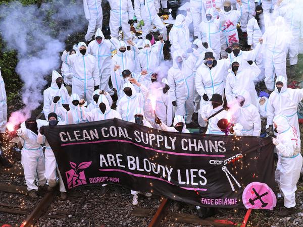 Klimaschutzaktivisten von der Gruppe „Ende Gelände“ stehen auf den Gleisen am Kohlekraftwerk Scholven und halten ein Banner mit dem Aufschrift „Clean Coal Supply Chains Are Bloody Lies“ hoch. 