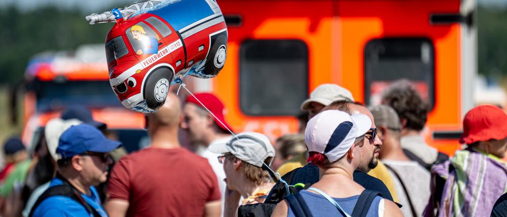 Ein Besucher läuft auf dem Erlebnistag der Berliner Feuerwehr auf dem Gelände am ehemaligen Flughafen Tegel mit einem Ballon in Form eines Feuerwehrfahrzeugs.