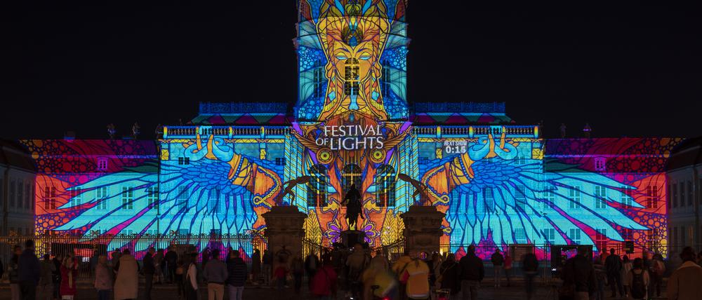 Zahlreiche Menschen schauen sich beim Festival of Lights die Illumination auf der Fassade vom Schloss Charlottenburg an. 