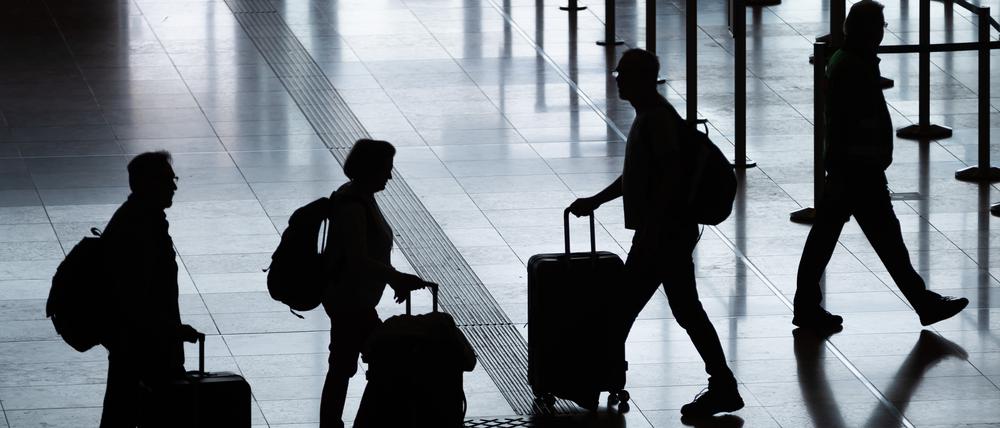 Fluggäste gehen mit Rollkoffern am Flughafen Berlin Brandenburg (BER) „Willy Brandt” durch das Terminal 1. 