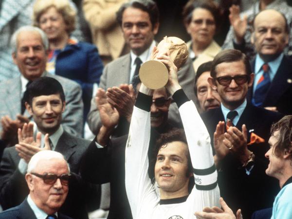 Kapitän Franz Beckenbauer hebt an der Seite von Torhüter Sepp Maier und dem englischen FIFA-Präsidenten Stanley Rous im Olympiastadion nach dem Endspiel der Fußball-WM den 1974 eroberten WM-Pokal hoch. 