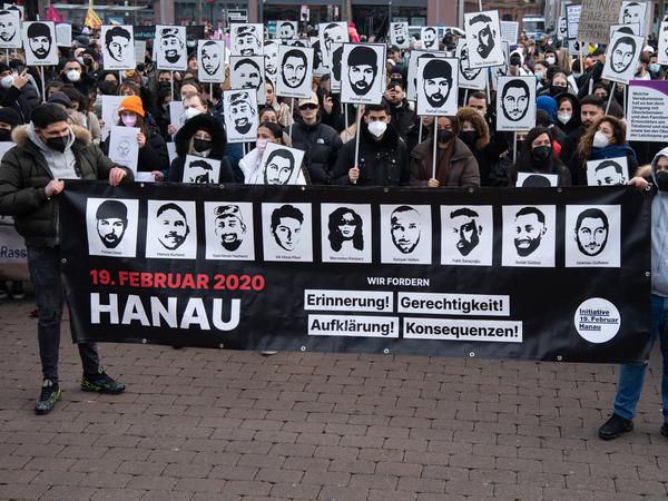 Mit Plakaten und Bildern der Ermordeten erinnern Teilnehmer einer Gedenkveranstaltung auf dem Marktplatz von Hanau im Jahr 2020.
