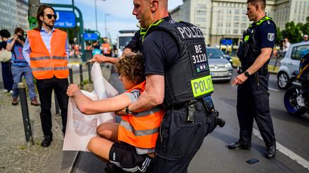 Ein Polizist schleift einen Aktivisten der „Letzten Generation“ von der Straße.