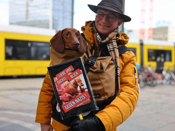 Mit „Liebe und Dackelblick gegen Nazis“ möchten ein Demonstrant und sein Hund in Berlin am 21. Januar 2024 gegen Rechtsextremismus demonstrieren.